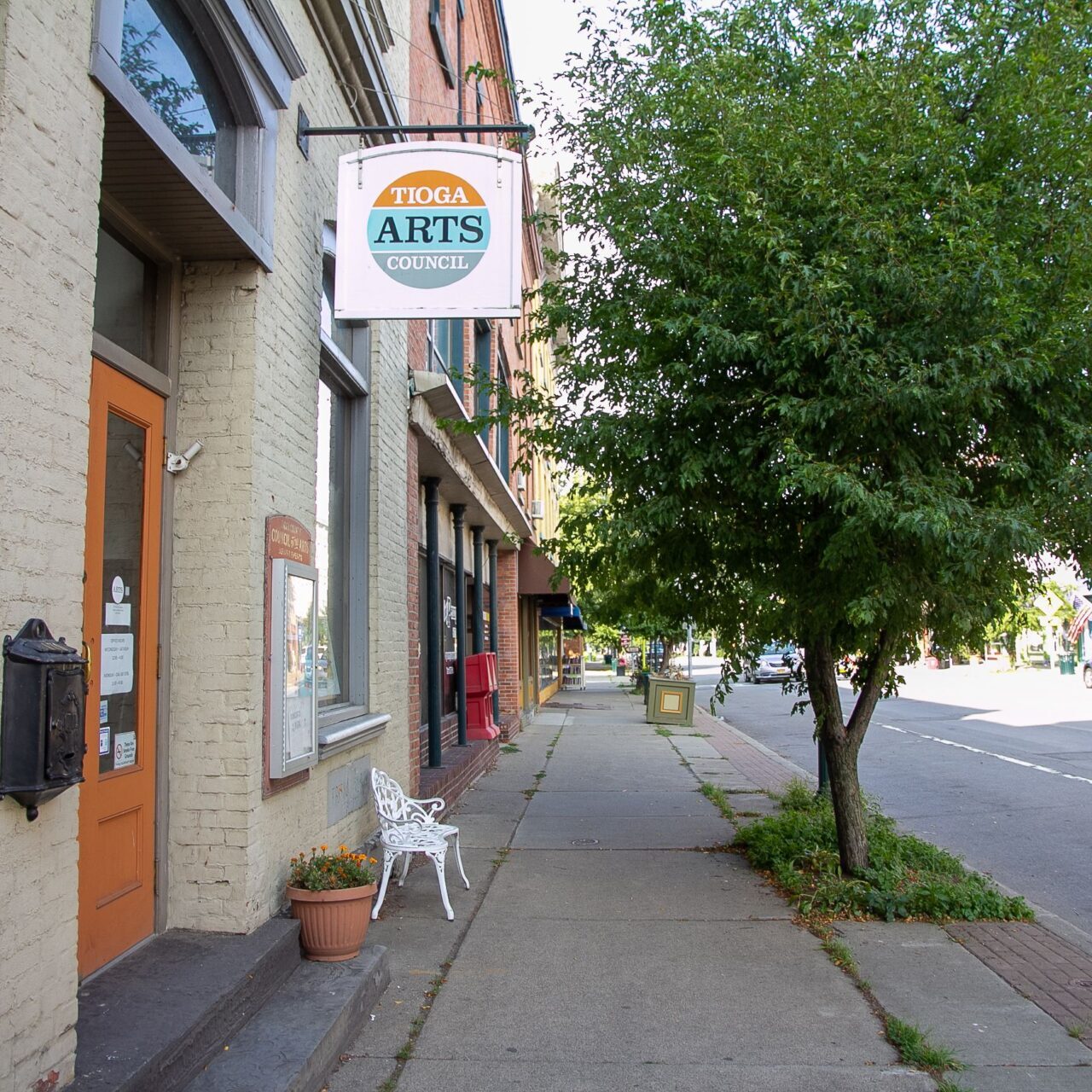 Exterior of grey brick building with handing sign that reads "tioga arts council"